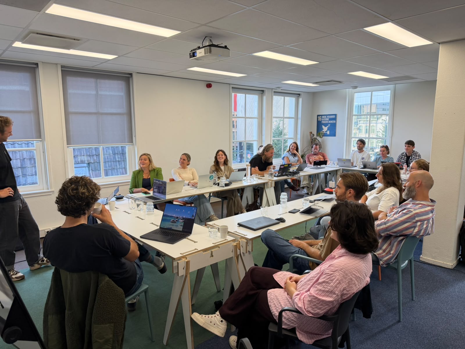 Het GoodUp-team volgt een workshop, met laptops rond een U-vormige tafel.