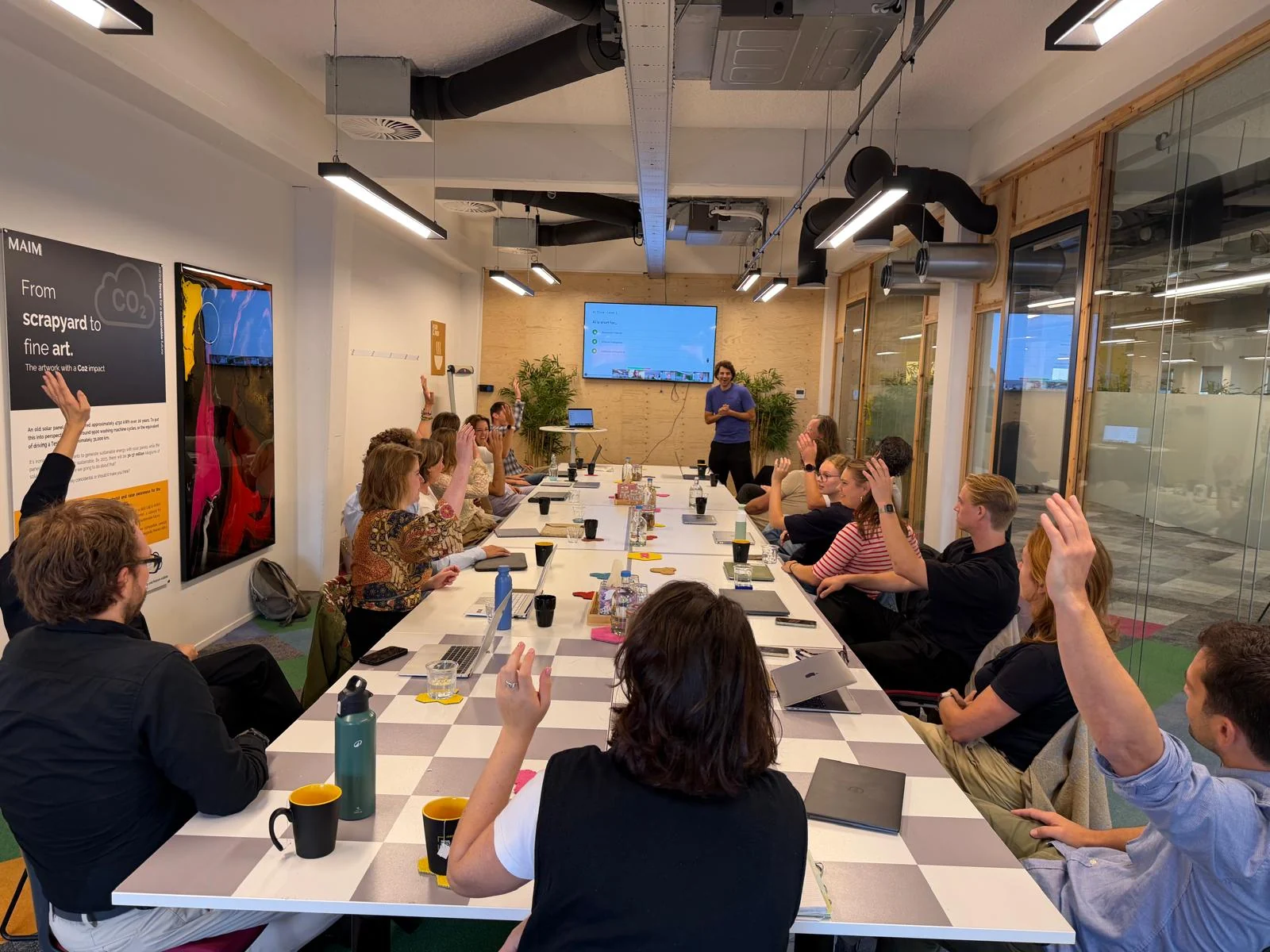 GoodUp workshop participants raising their hands around a table during an AI session